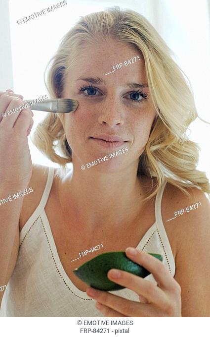 Blonde woman applying avocado mask