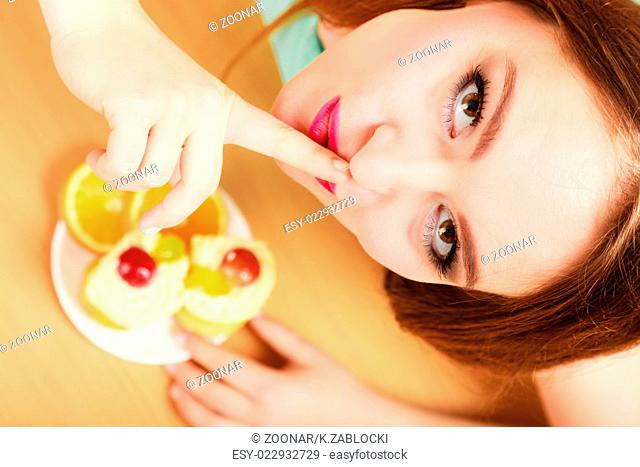 Woman eating cake showing quiet sign. Gluttony