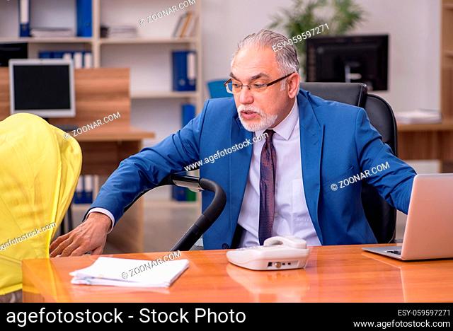 Old businessman employee looking after newborn at workplace