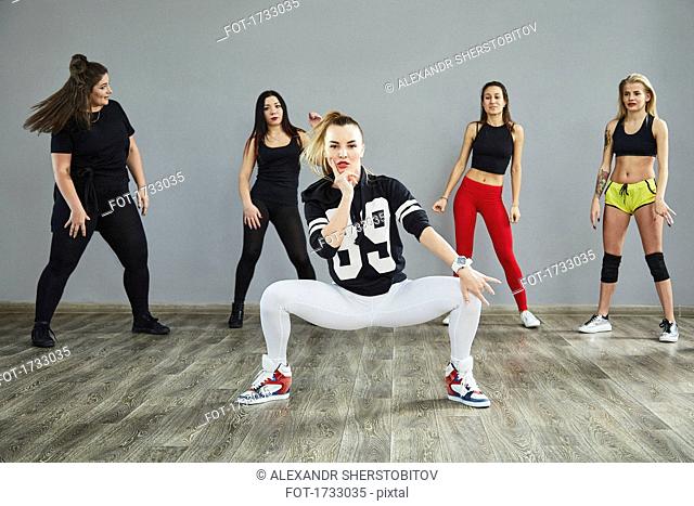 Full length of confident young dancers dancing against wall at studio