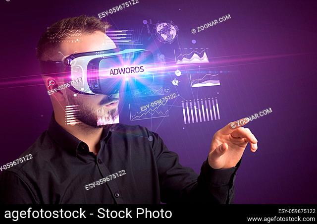 Businessman looking through Virtual Reality glasses with ADWORDS inscription, new business concept