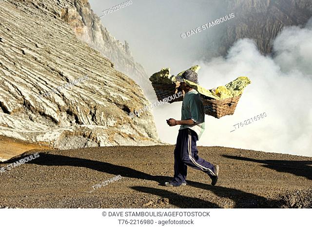 Miner carrying a heavy load of sulphur at the Kawah Ijen volcanic crater, Java, Indonesia