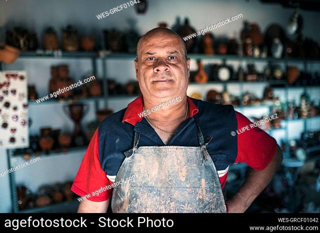 Potter with hand on hip standing in pottery