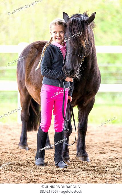 Shetland Pony. Child in riding dress standing next to black adult. Germany
