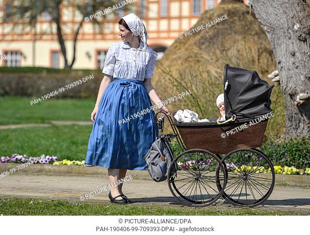 06 April 2019, Brandenburg, Lübbenau: Anja Harms and her ten-month-old daughter are in Sorbian costume in a historic pram from 1900
