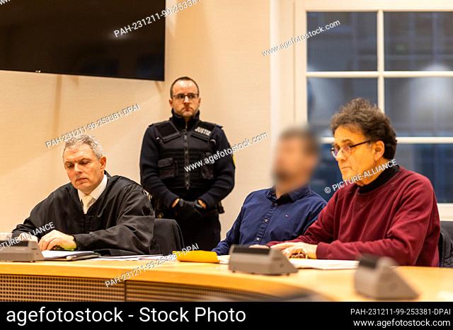 11 December 2023, Baden-Württemberg, Waldshut-Tiengen: A defendant (2nd from right) sits between an interpreter (r) and his defense lawyer (l) while a court...