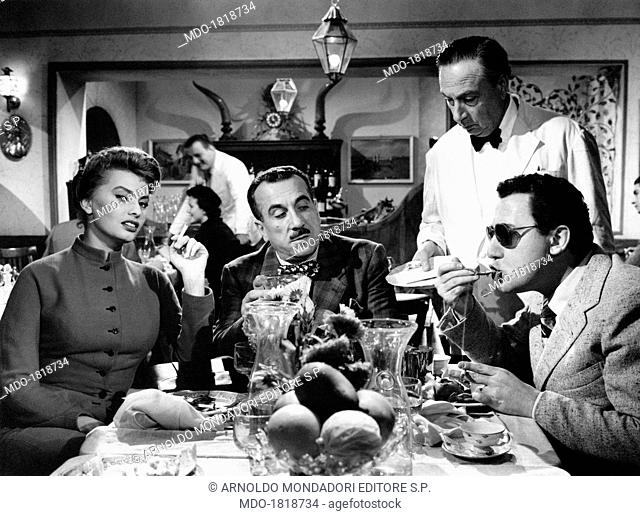 Italian actors Sophia Loren (Sofia Villani Scicolone), Alberto Sordi, and Peppino De Filippo sitting at the table in the film The Sign of Venus. 1955