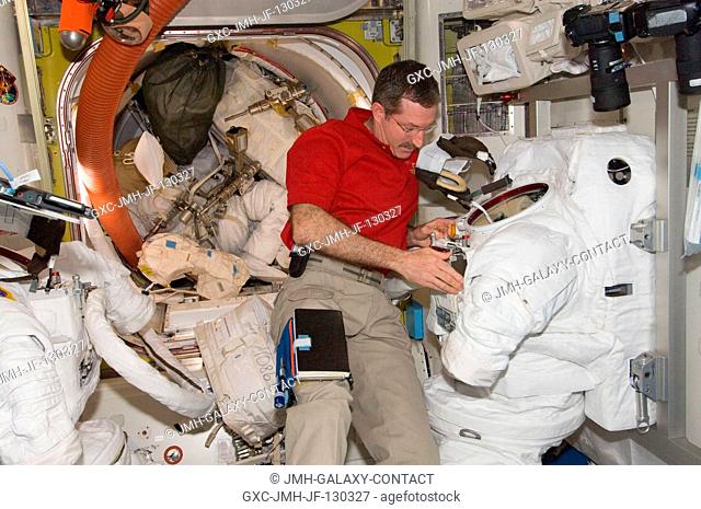 NASA astronaut Dan Burbank, Expedition 30 commander, performs routine in-flight maintenance on Extravehicular Mobility Unit (EMU) equipment in the Quest airlock...