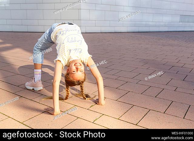 Happy girl standing in bridge position on floor