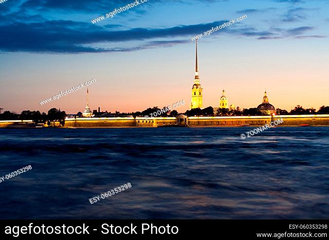 Peter and Paul fortress with the Palace promenade at sunset on a background of pure pink sky with reflection in the water of the Neva river during the white...