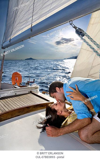 Couple laying on sailboat, kissing