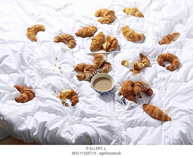 Croissants and a bowl of coffee on a bedspread