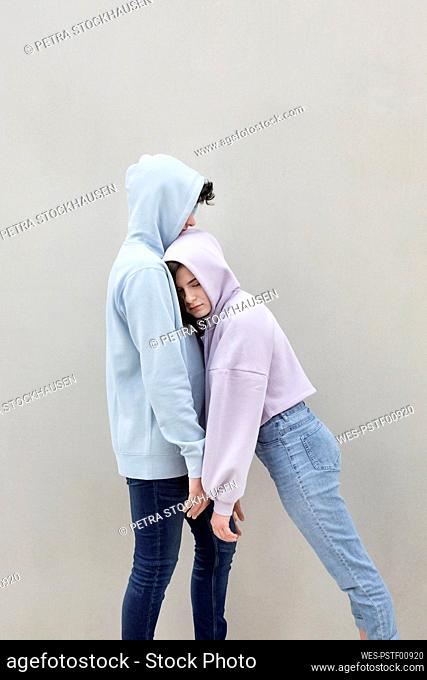 Teenage girl leaning on boyfriend by wall