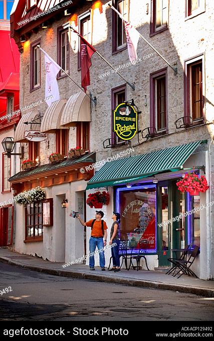 Couple in front of a small, independent grocery store on rue des Jardins in the historic Upper Town of Old Quebec City, Province of Quebec, Canada
