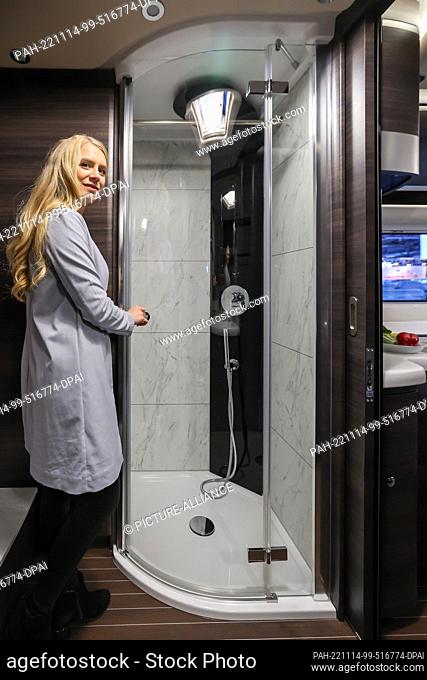 14 November 2022, Saxony, Leipzig: A woman looks at the shower cabin with marble tiles in a Concorde Liner 1090 GL motorhome for a good 480