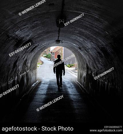 Vertrijk, Boutersem, Flemish Brabant Region, Belgium - 01 29 2022: Man walking in the narrow tunnel down the railway tracks