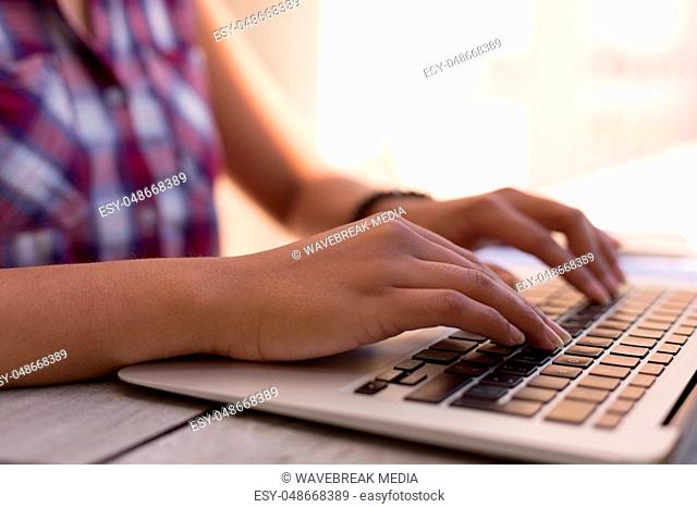 Woman typing on laptop on desk at home