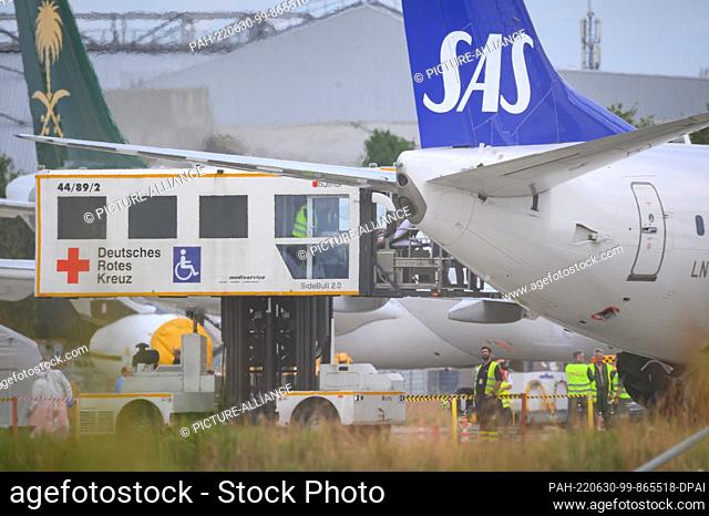 30 June 2022, Hamburg: A patient is pushed from the SAS aircraft into a DRK (German Red Cross) lift truck on the apron. An aircraft brought injured people from...