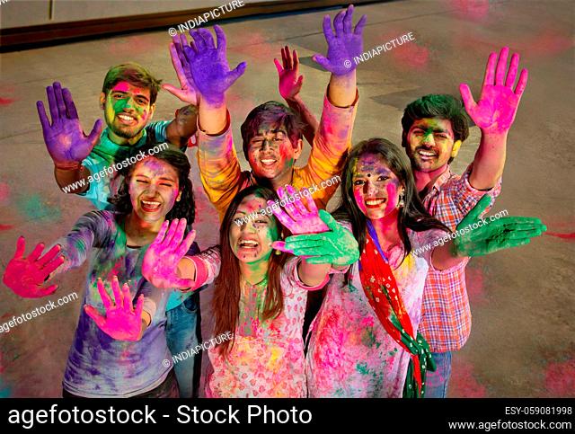 A HAPPY GROUP OF FRIENDS SHOWING HANDS FILLED WITH COLOUR ON CAMERA