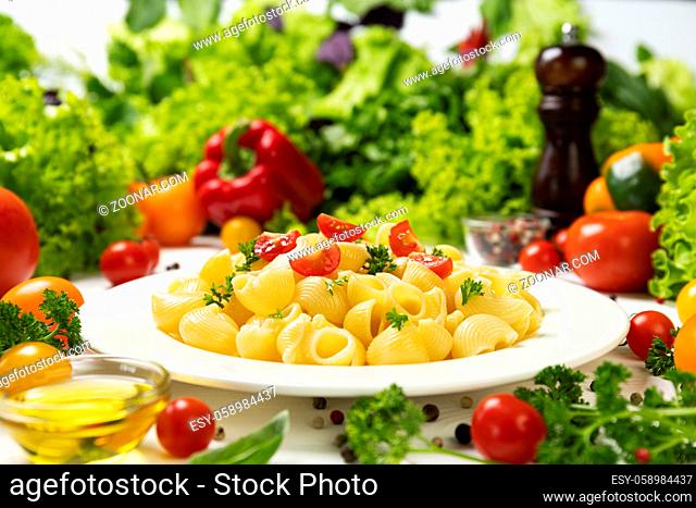 Plate of cooked italian pipe rigate pasta with tomatoes and basil leaves