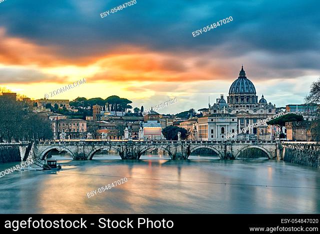 St. Peter's cathedral and Tiber river with high water at evening with dramatic sunset sky. Saint Peter Basilica in Vatican city with Saint Angelo Bridge in Rome