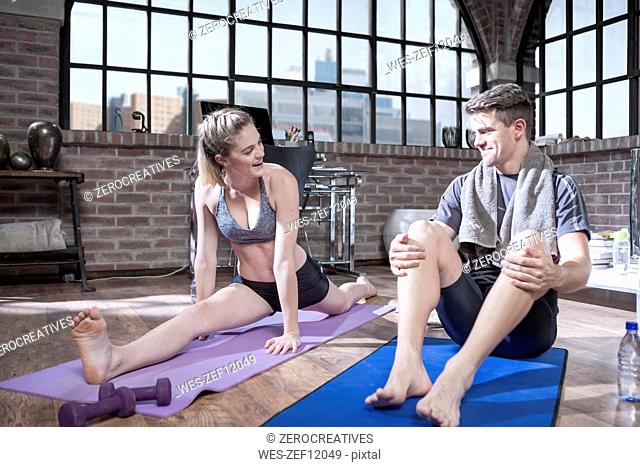 Young man watching woman doing splits in exercise room