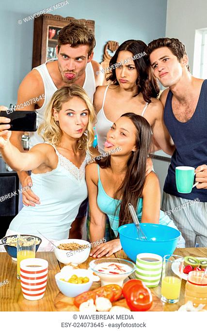 Friends taking selfie through mobile phone while cooking