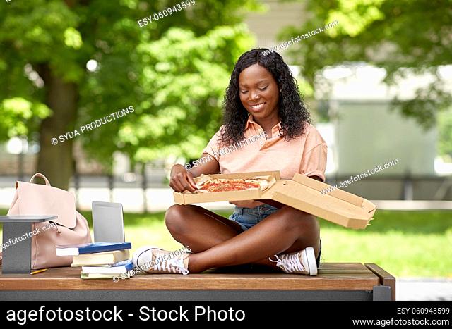 african student girl eating takeaway pizza in city