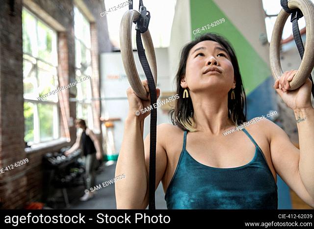 Woman exercising at gymnastics rings in gym
