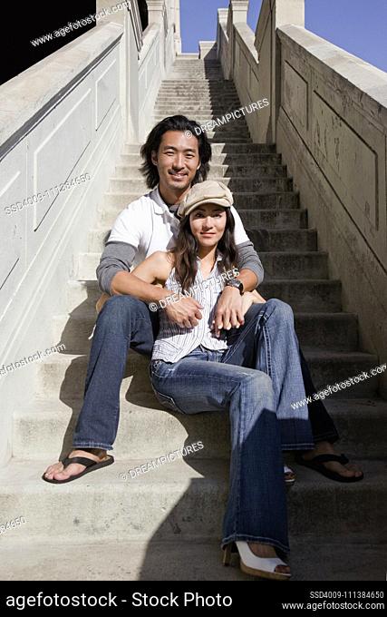Korean couple sitting on stairway outdoors