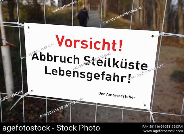 16 November 2020, Mecklenburg-Western Pomerania, Stralsund: A sign with the words ""Caution! Abort steep coast danger to life"" hangs on a fence