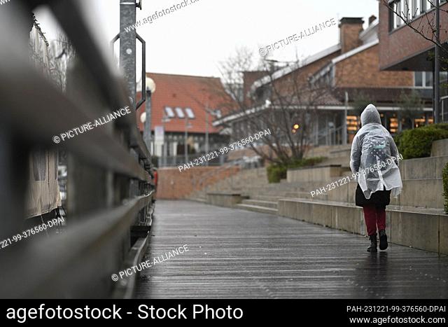 21 December 2023, Lower Saxony, Leer: A woman walks through the rain. The German Weather Service is expecting storms, particularly on the North Sea coast