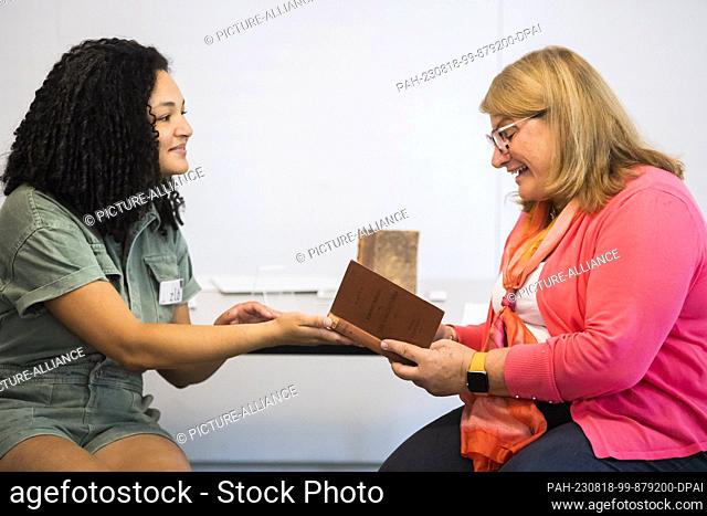 18 August 2023, Berlin: Carolyn Hollander (r), granddaughter of Cäcilie Holländer, receives two books from Cäcilie Holländer, her grandmother