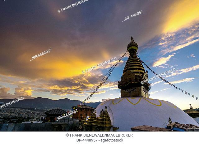 Stupa of Swayambhunath temple, Monkey Temple, decorated with tibetan prayer flags, orange clouds above, Kathmandu, Nepal