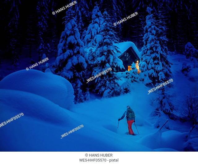 Austria, Salzburg State, snowshoeing, woman near hut at night