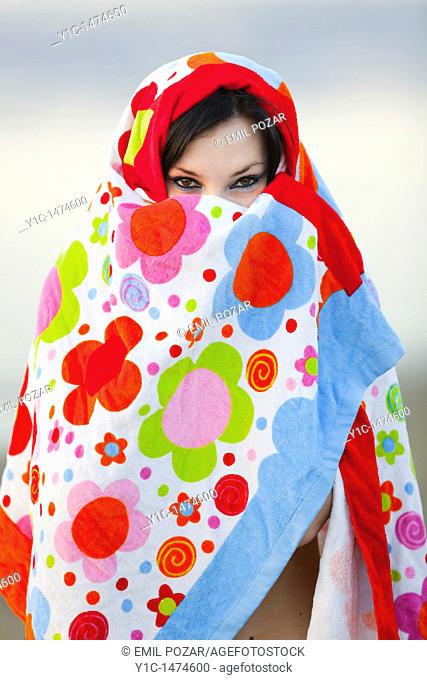 Attractive young woman enveloped with a colorful towel