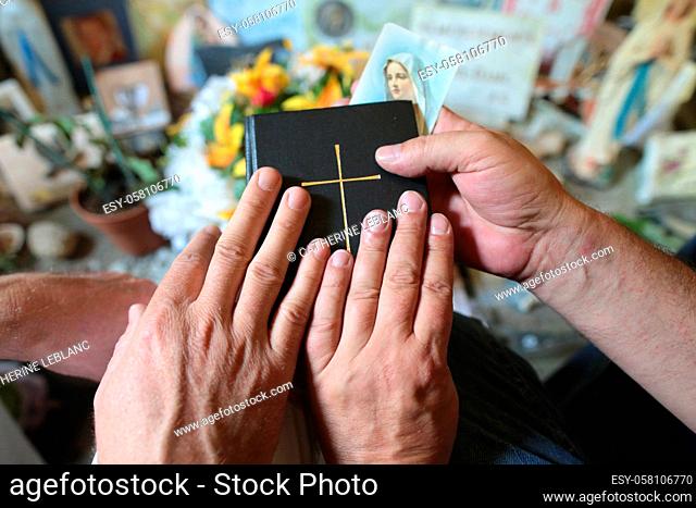 Two pilgrims praying with their hands on the Bible. Haute-Savoie. Auvergne Rhône-Alpes. France. Europe