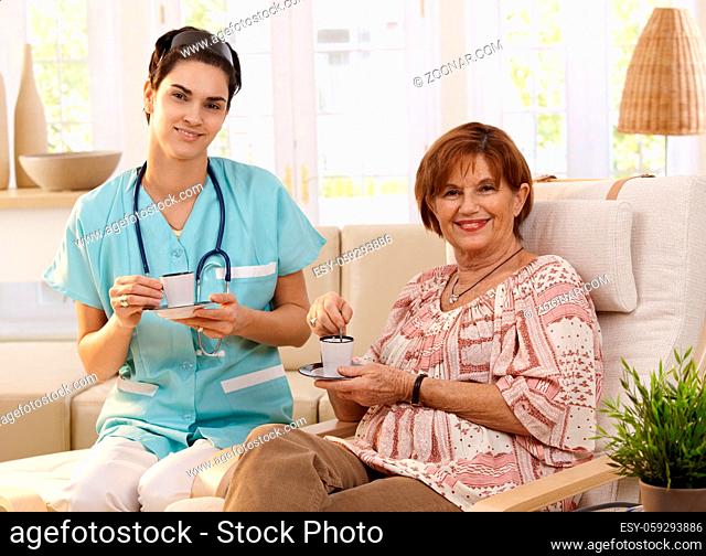 Nurse and senior patient drinking coffee after examination at home, smiling
