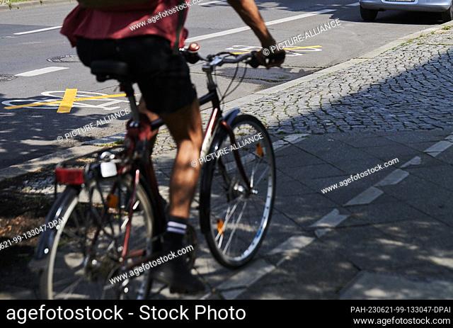 21 June 2023, Berlin: A cyclist rides on an old stunted bike lane on Ollenhauer Street. The new bike lane on the street has been taped over with yellow crosses