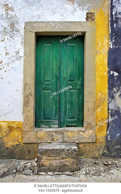 Green Wood Door with Hand Carved Stone against a Texured Wall in the Medieval Village Of Obidos