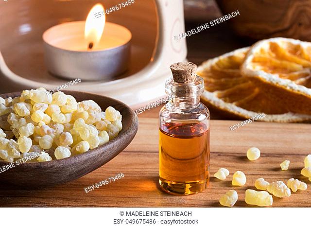 A bottle of frankincense essential oil with frankincense resin and an aroma lamp in the background