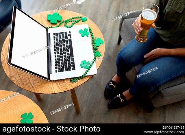 Caucasian woman holding beer on st patrick's day laptop video call with copy space on screen