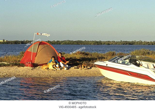 Couple on shore with tent and fire after boating with motor boat to relax - 01/01/2014