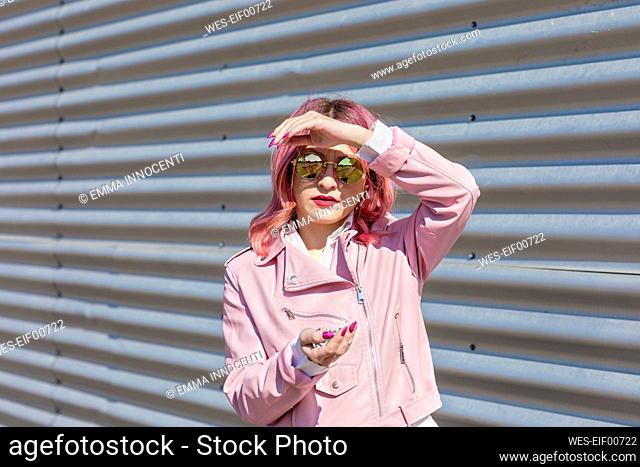 Young woman with sunglasses holding confetti during sunny day