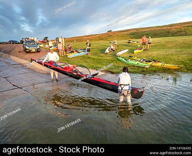 Pickstown, SD, USA - July 13, 2019: A couple launching their tandem outrigger canoe on Missouri River below Fort Randall Dam for 50 mile river race