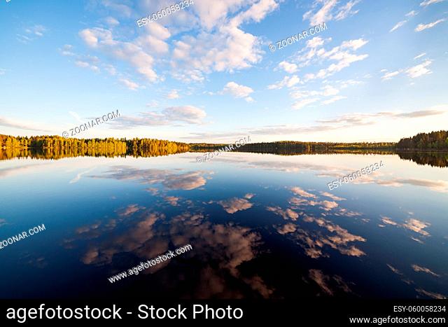 Still lake perfect reflection of sky and clouds at summer evening Finland