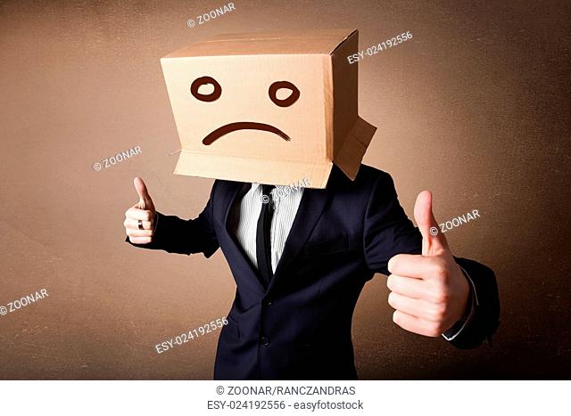 Businessman gesturing with cardboard box on his head with sad face