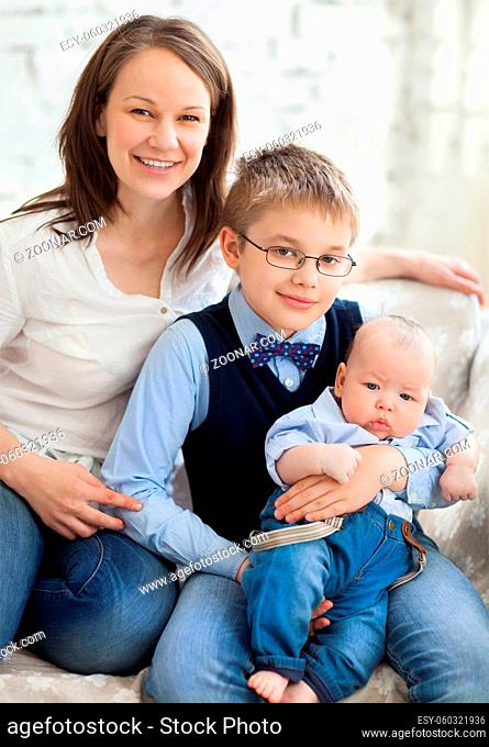 Happy mother with her children having fun in living room at home, laughing