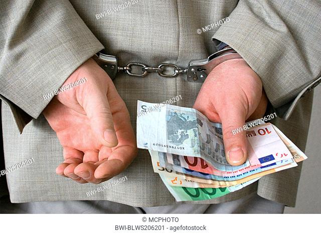 handcuffed businessman holding Euro bills in his hand