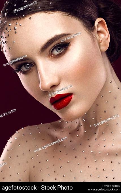 Portrait of a beautiful girl with a bright make-up, red lips and crystals on the body. The beauty of the face. Photos shot in the studio